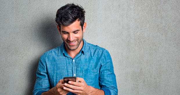Man kijkt lachend naar zijn telefoon. Man kijkt lachend naar zijn telefoon.